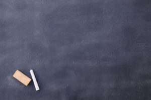 A chalkboard with chalk and a piece of paper.