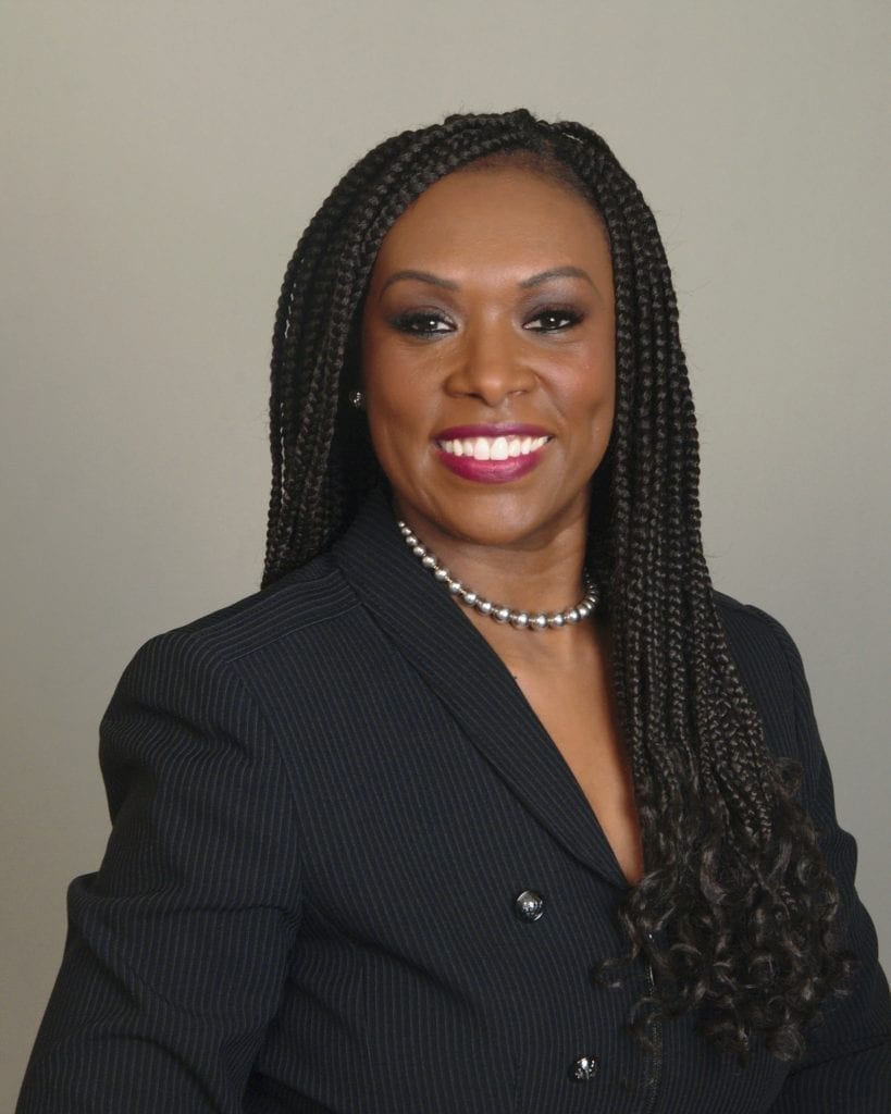 A woman with long braids wearing a black suit.