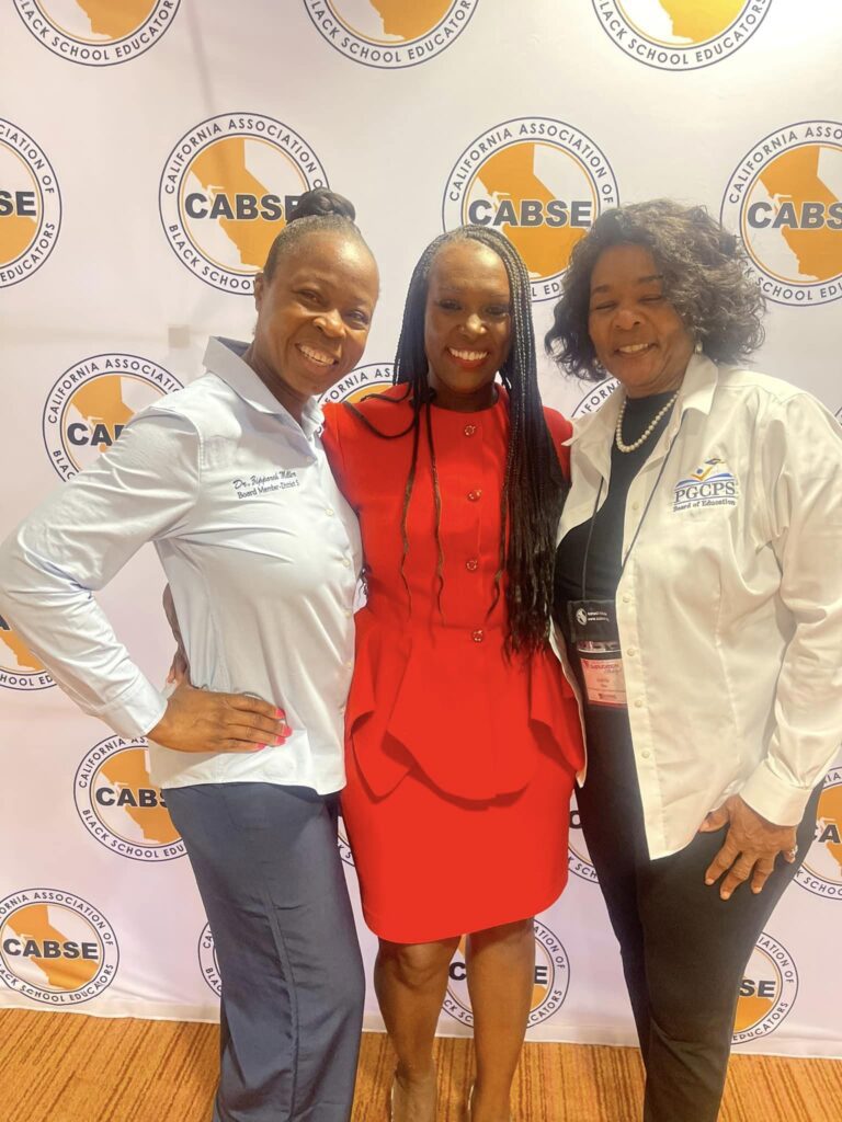 Three women posing for a picture in front of the caisse logo.